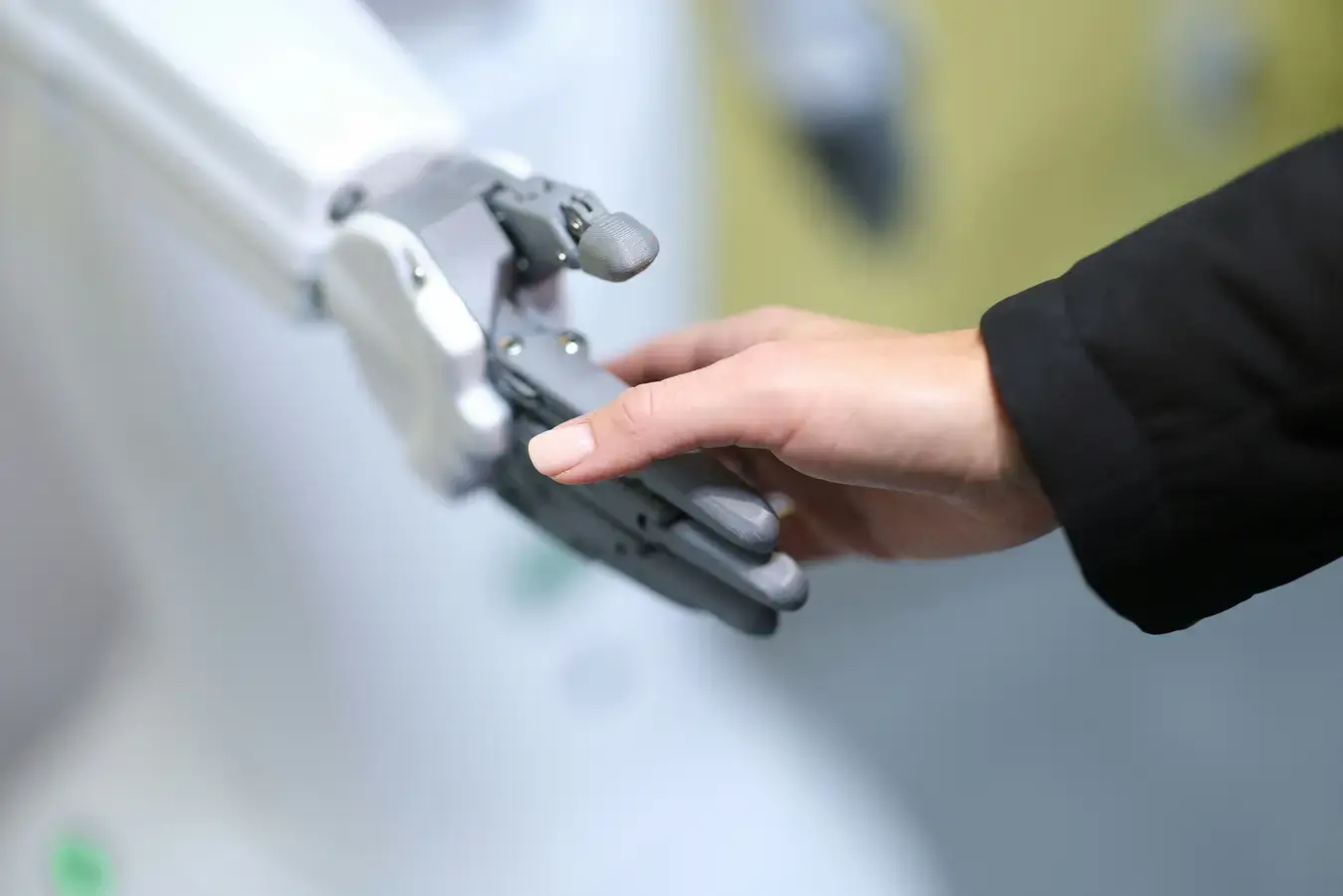 A close-up image shows a human hand reaching towards a robotic hand, highlighting the interaction between human and artificial intelligence.